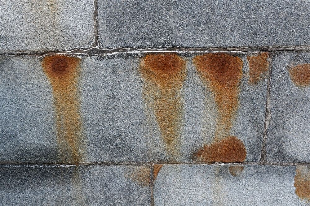 Escorridos marrom-alaranjados de ferrugem sobre placas de concreto cinza