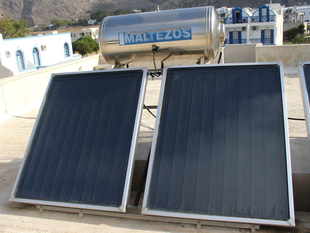 Dois coletores solares planos sobre uma laje, com um reservatório de inox ao fundo