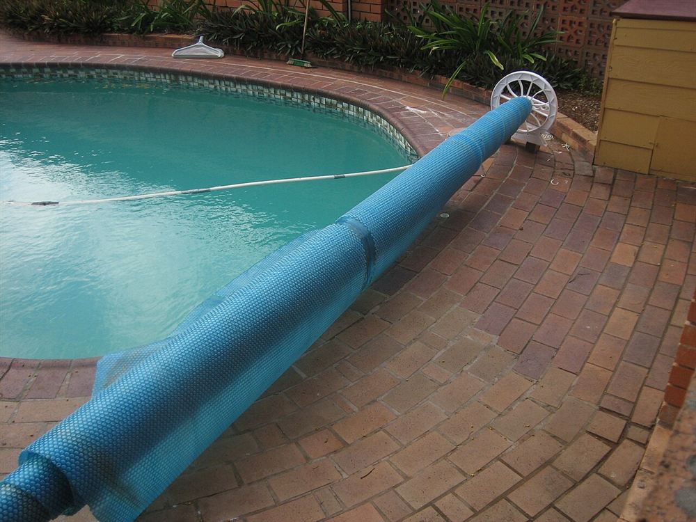 Capa térmica azul enrolada num carretel à beira de uma piscina residencial