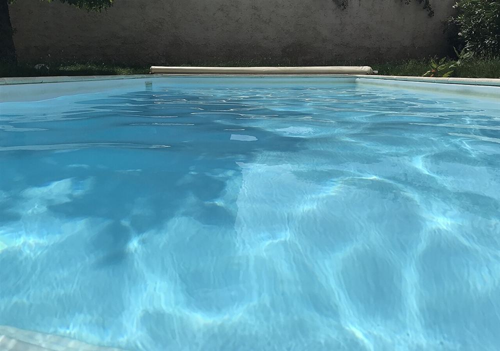 Piscina com água azul cristalina, com o reflexo do sol desenhando o fundo