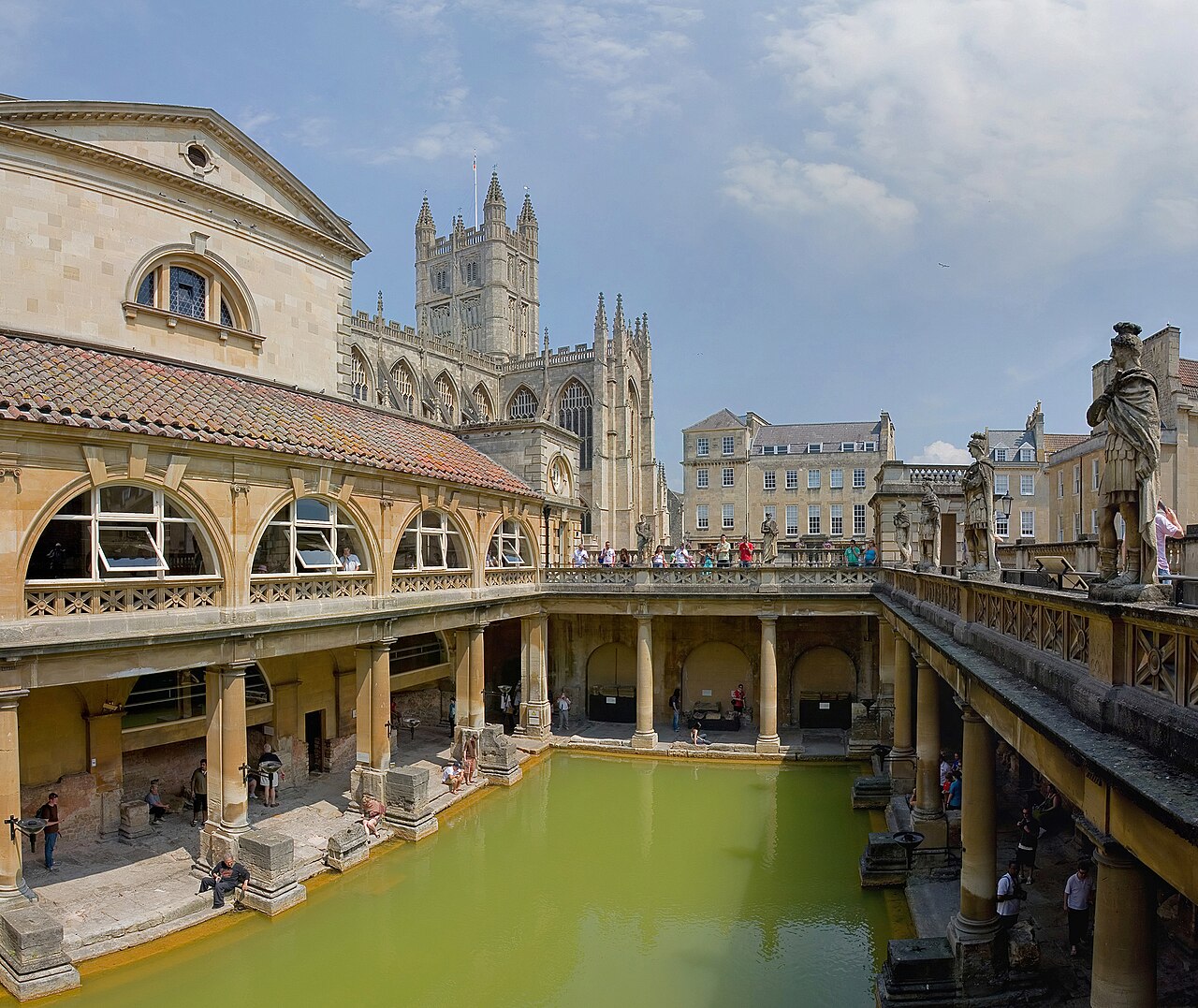 O Grande Banho das termas romanas de Bath, na Inglaterra, com água esverdeada cercada por colunas e estátuas