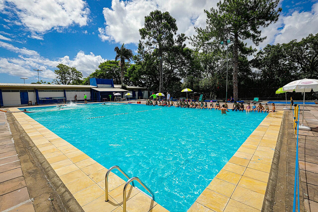 Piscina pública ao ar livre em Porto Alegre, com crianças sentadas na borda