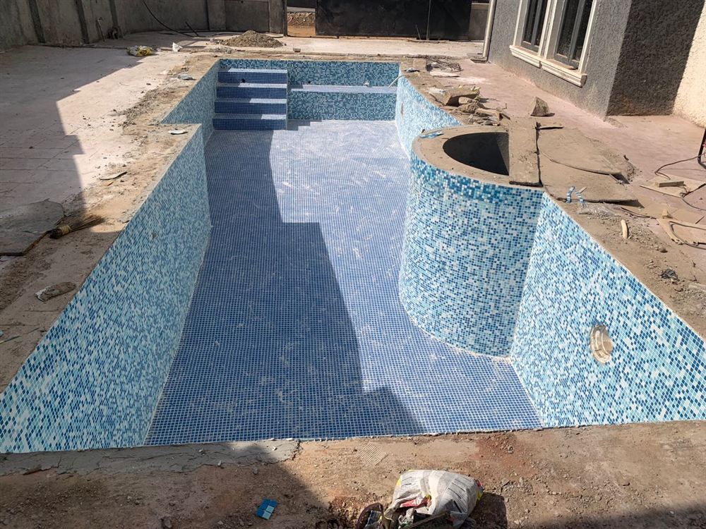 Piscina de alvenaria vazia revestida de pastilhas azuis, ainda em obra