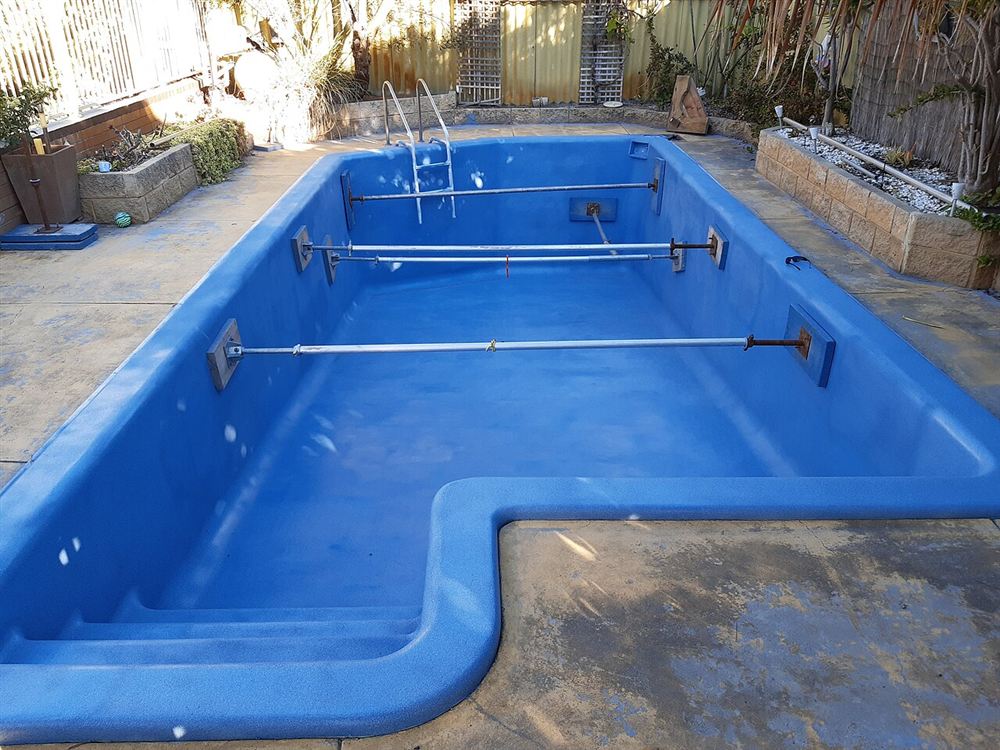 Casco de piscina de fibra azul, vazio e recém-recuperado, com escada moldada