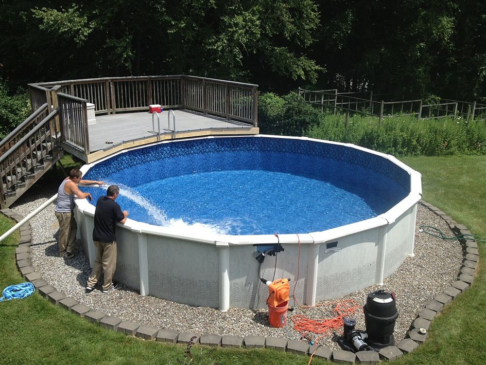 Duas pessoas enchendo uma piscina acima do solo revestida de vinil estampado