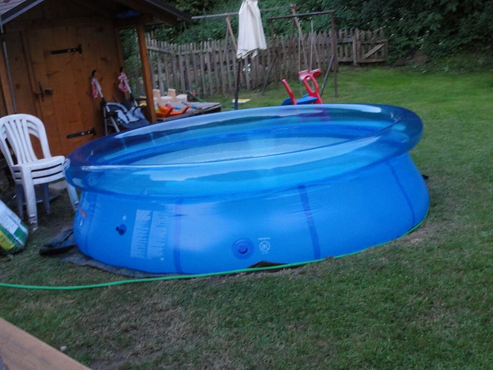Piscina inflável azul cheia de água sobre a grama de um quintal
