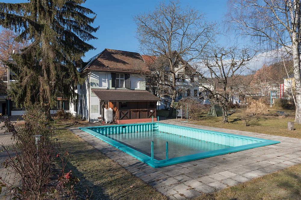 Piscina externa num jardim com árvores sem folhas, num dia frio de inverno
