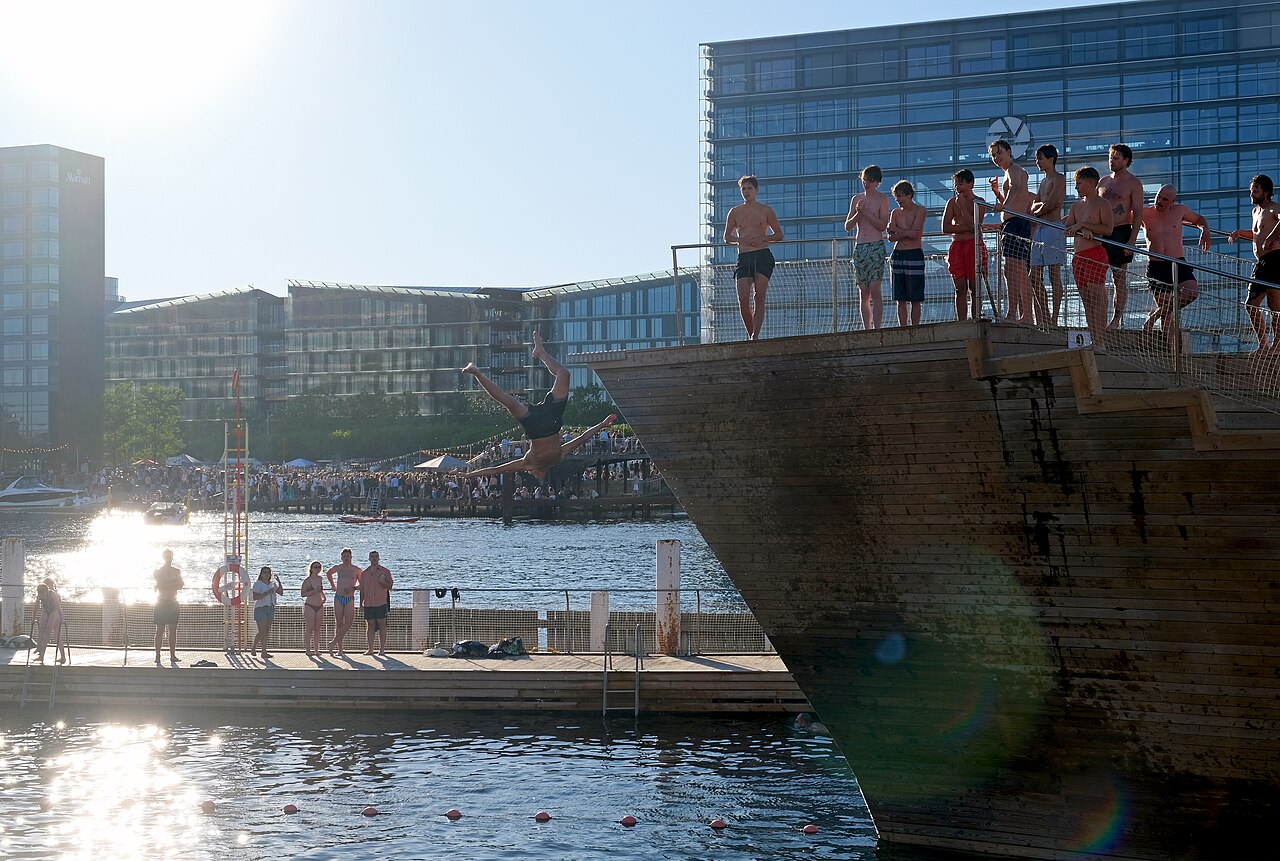 Banhistas nas plataformas da piscina de Islands Brygge, no porto de Copenhague, com prédios ao fundo