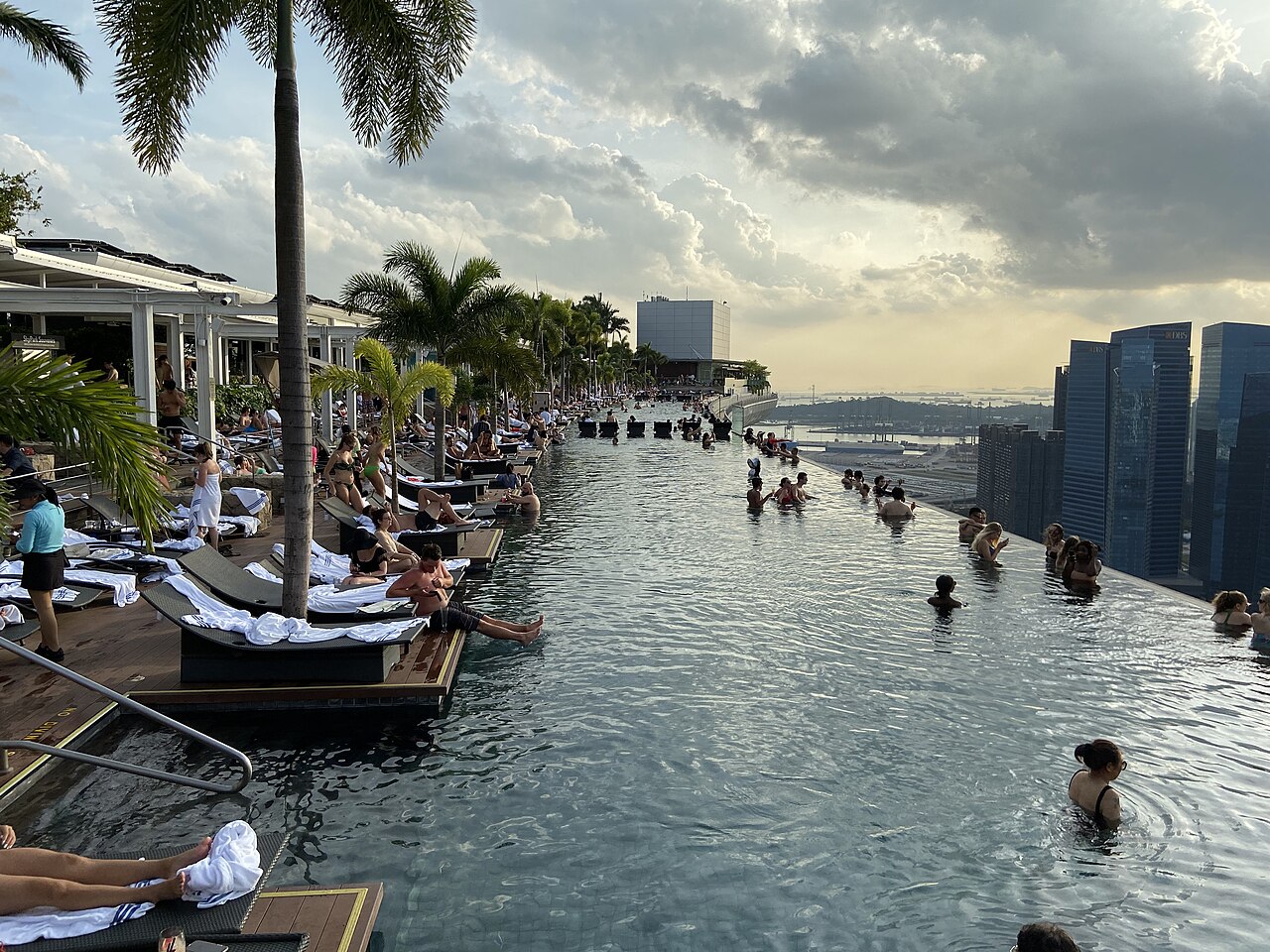Piscina de borda infinita no alto do Marina Bay Sands, com banhistas e os prédios de Singapura ao fundo