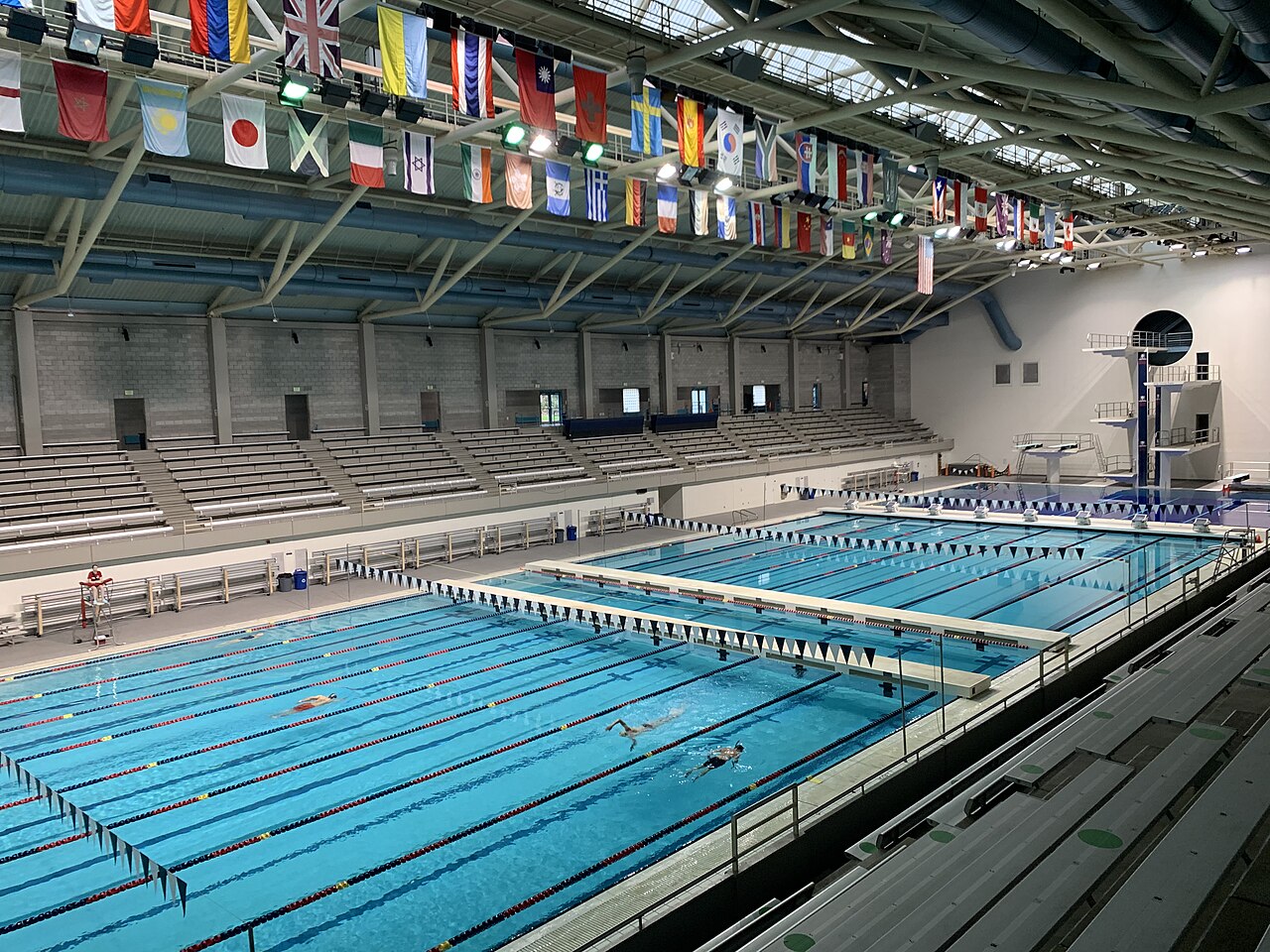 Piscina coberta de competição com raias e fundo claro, com a água em tom azul-ciano