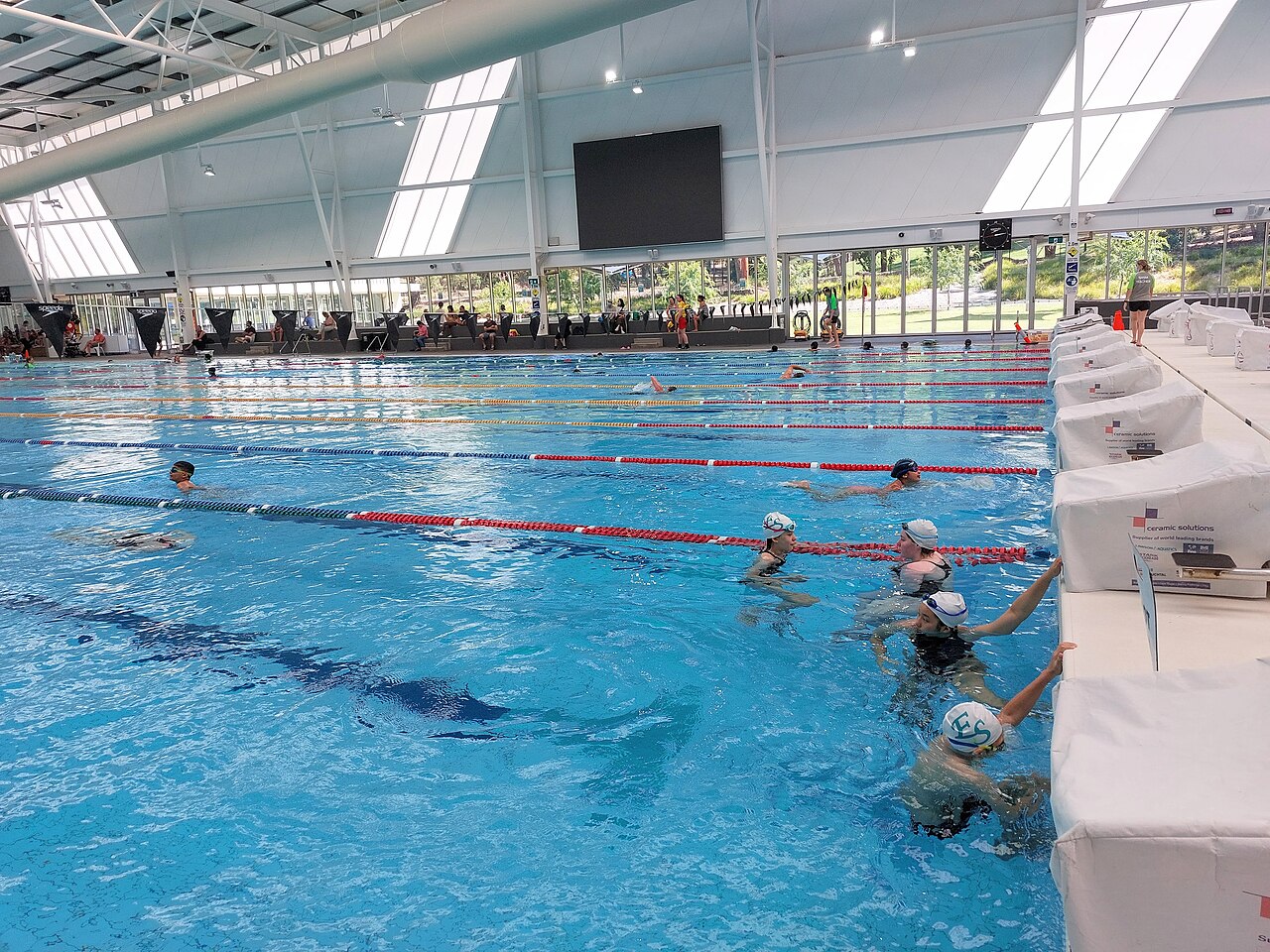 Piscina pública coberta com raias e nadadores